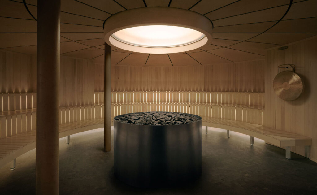 Circular sauna interior at Recess social wellness club in Montreal, designed by Future Simple Studio, with a central heater beneath a circular oculus.