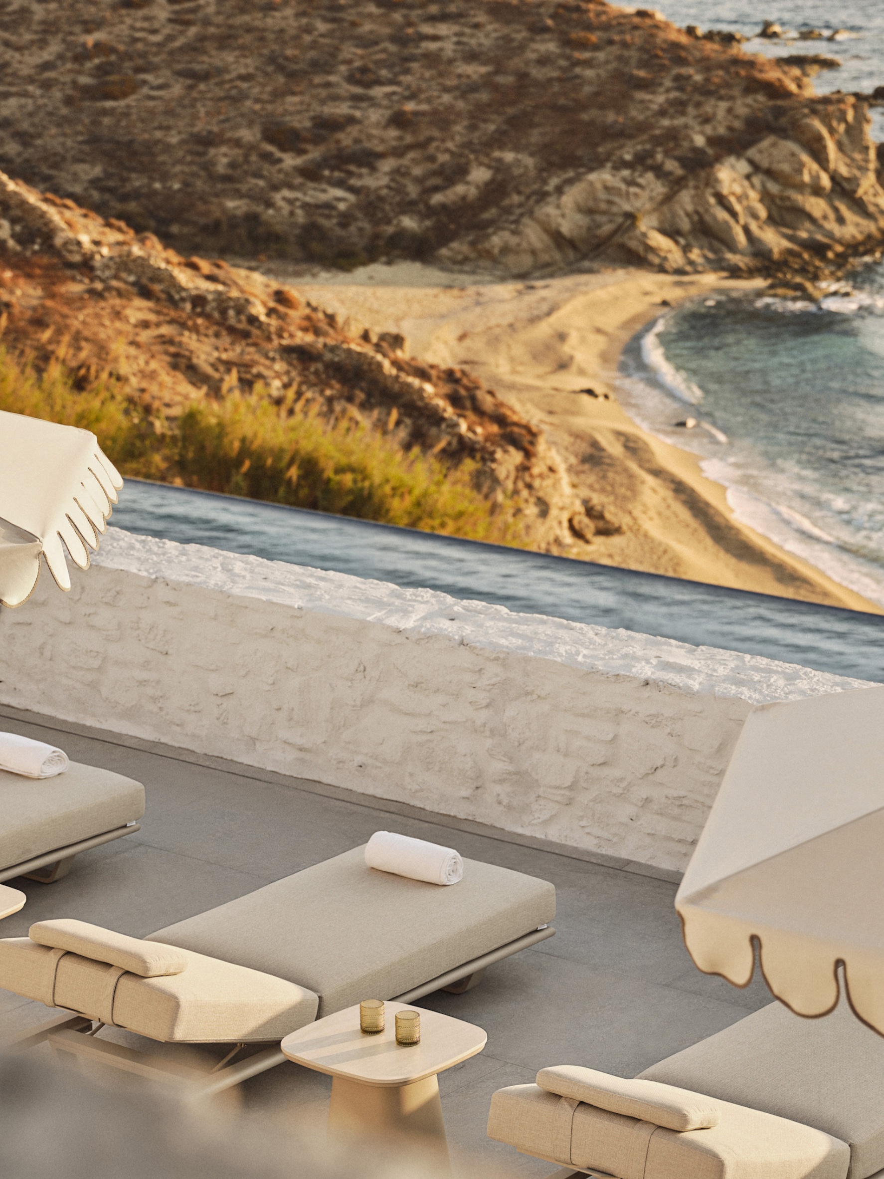 Luxury sun loungers beside an infinity pool overlooking Kalo Livadi Bay at Four Seasons Hotel Mykonos