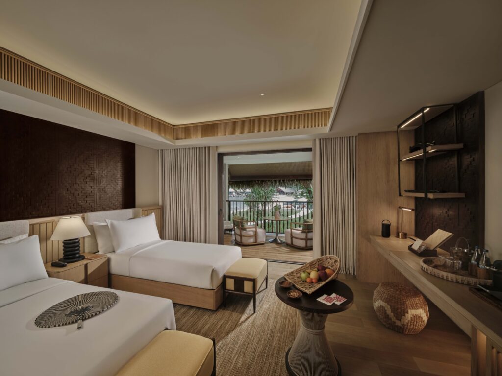 Twin guest room at Lagen Island Resort in El Nido, Palawan, featuring natural wood interiors and a private balcony overlooking the resort.
