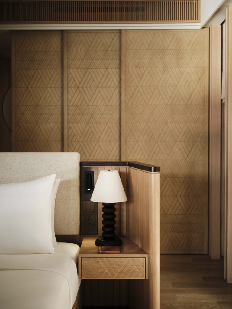 Water villa bedroom at Lagen Island Resort in El Nido, Palawan, featuring carved wood panels and natural woven details.