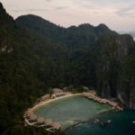 Aerial view of Lagen Island Resort in El Nido, Palawan, with overwater villas surrounding a turquoise cove beneath limestone cliffs.