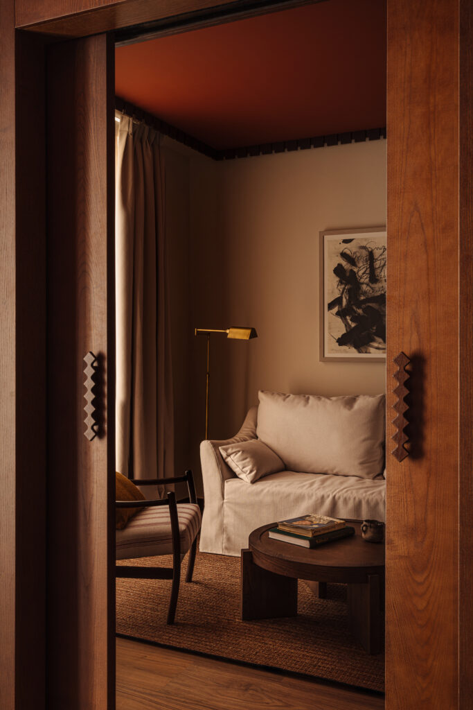 King Leonor suite living room at Palacio de Godoy, featuring a cream slipcovered sofa, terracotta ceiling, cherry-wood sliding door, and woven sisal rug.