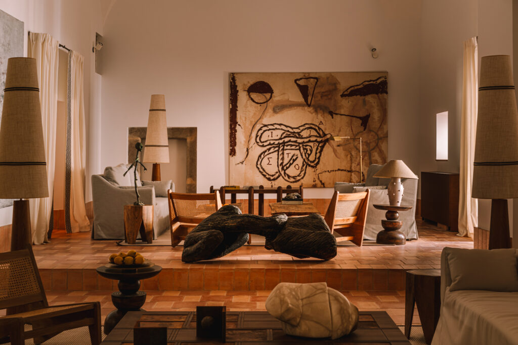 Sculpture-filled lounge at Palacio de Godoy, Cáceres, Curio Collection by Hilton, with terracotta floors and tall linen lamps.