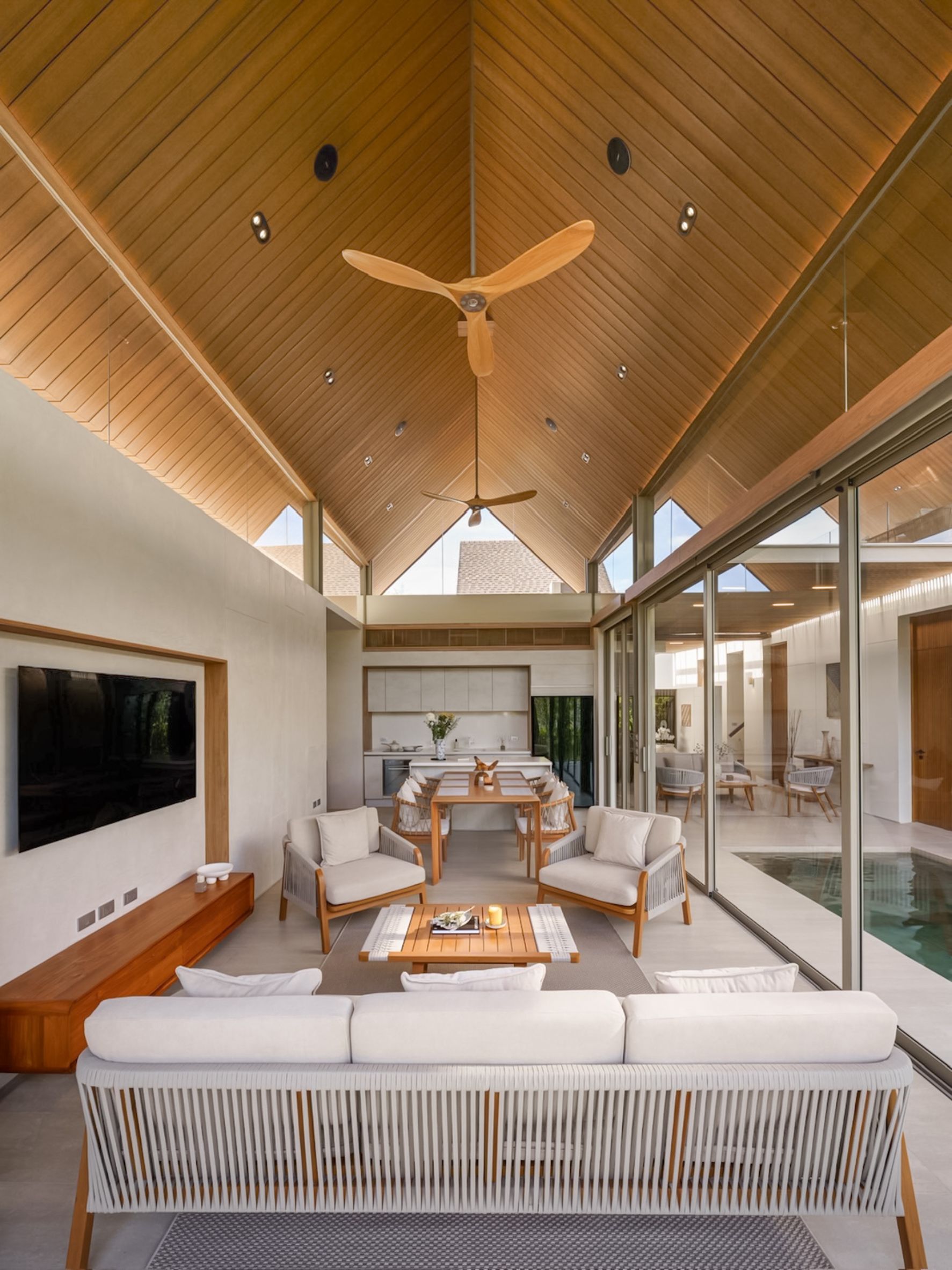 ANSAYA Phuket villa interior in Phuket, Thailand, featuring a high timber pitched ceiling, open-plan living and dining space, and private courtyard pool.