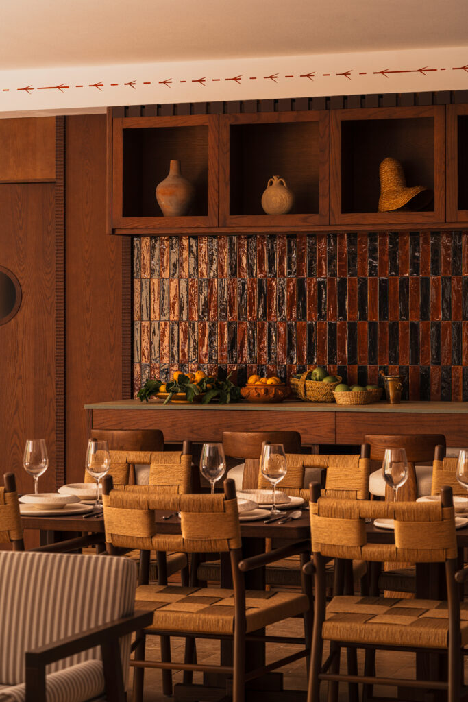 Breakfast area at Palacio de Godoy, Cáceres, with rush-seat chairs, a glazed tile backsplash, and displayed ceramic vessels.