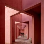Laiva Plaza hotel corridor by RA!, San José del Cabo, Mexico. Repeated pink stucco walls frame a receding passageway lined with ceramic vessels.