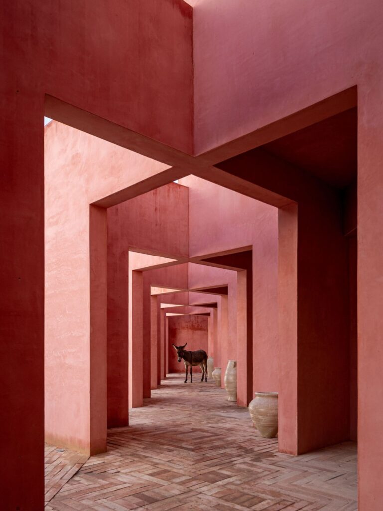 Laiva Plaza hotel corridor by RA!, San José del Cabo, Mexico. Repeated pink stucco walls frame a receding passageway lined with ceramic vessels.