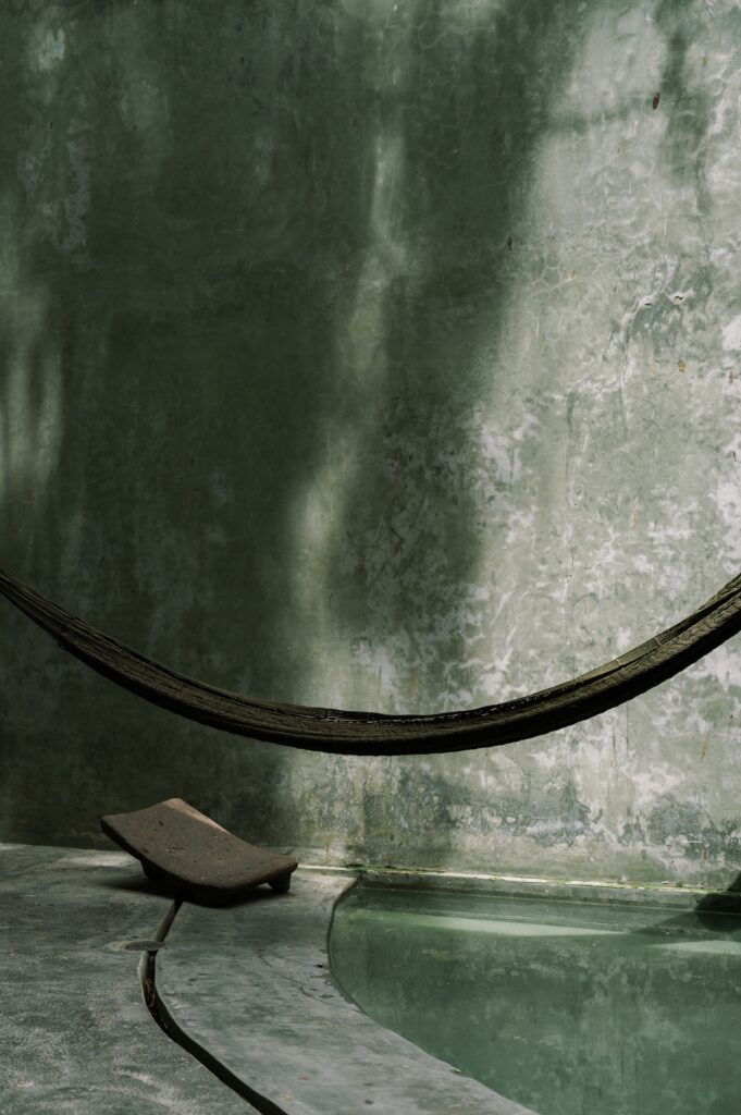 Casa Gruta in Yucatán, Mexico, featuring a suspended hammock above a curved plunge pool, textured concrete walls, and natural light inspired by the region’s cenotes.