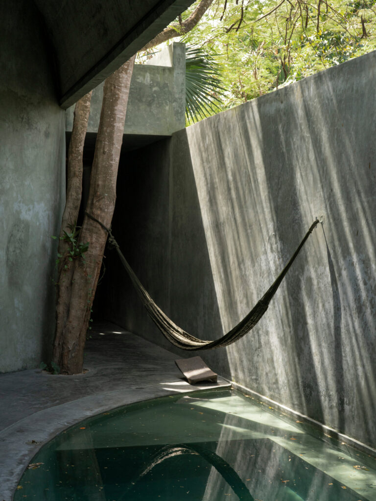 Casa Gruta in Yucatán, Mexico, designed by Salvador Román Hernández and Adela Mortera Villarreal, featuring a hammock suspended above a private pool in a concrete courtyard surrounded by tropical trees.