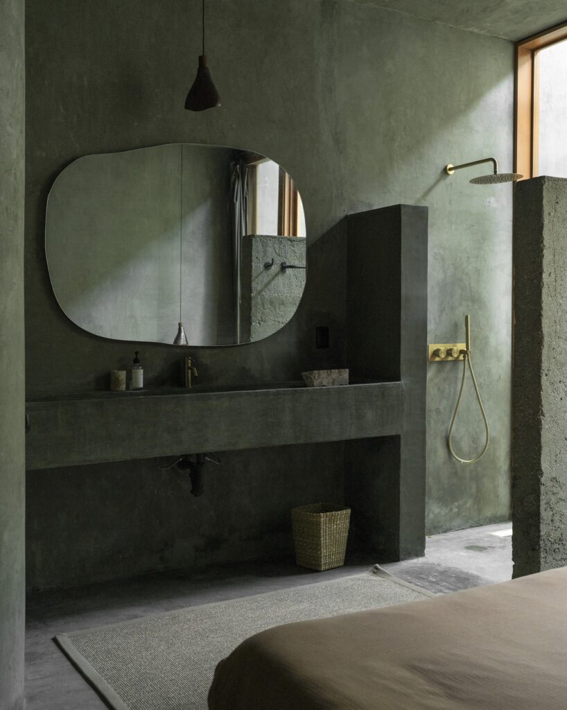 A built-in concrete vanity, and a walk-in shower with brass fixtures at Casa Gruta, Mexico.