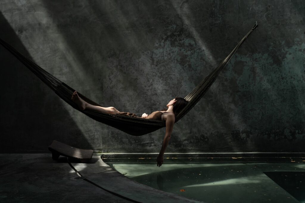 Casa Gruta in Yucatán, Mexico, featuring a woman relaxing in a suspended hammock above a cenote-inspired pool.